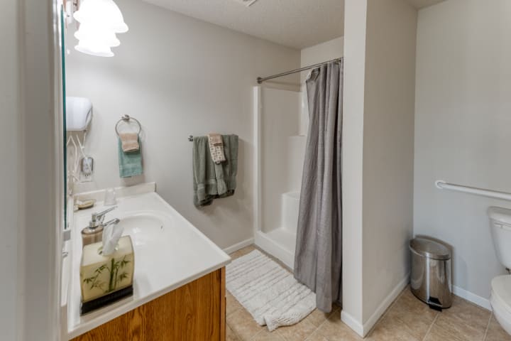 A modern bathroom with a shower and sink area, featuring towels and a curtain.