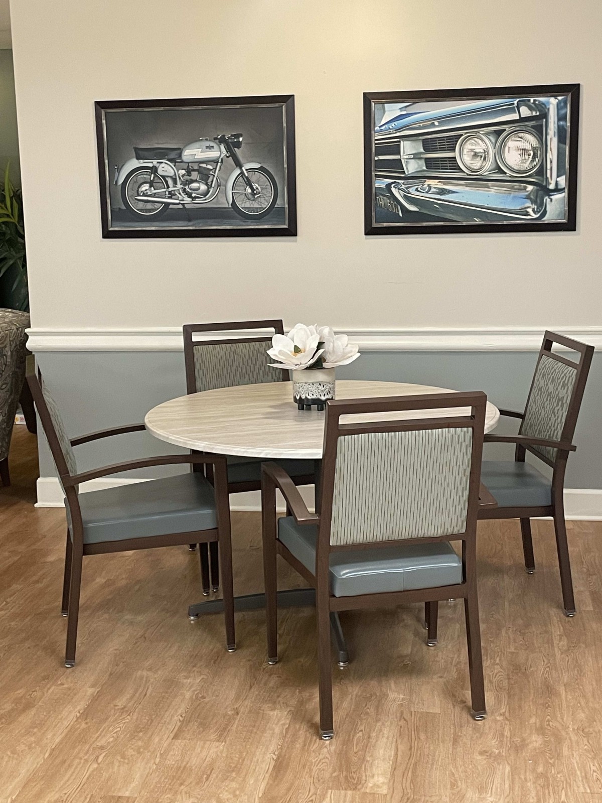 A cozy dining area with a round table, four chairs, and motorcycle artwork on the wall.