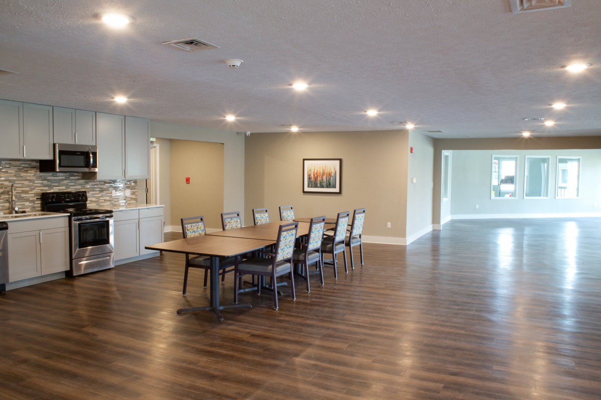 A spacious conference room with a long wooden table and chairs, featuring modern decor and bright lighting.