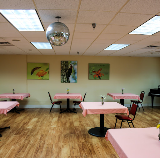 An empty restaurant with pink tablecloths and decorative artwork on the walls, featuring a disco ball hanging from the ceiling.