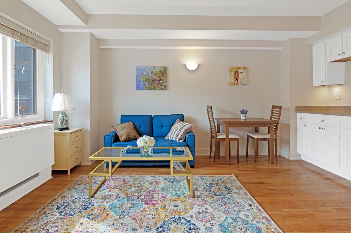 A cozy living room with a blue sofa and a dining area.