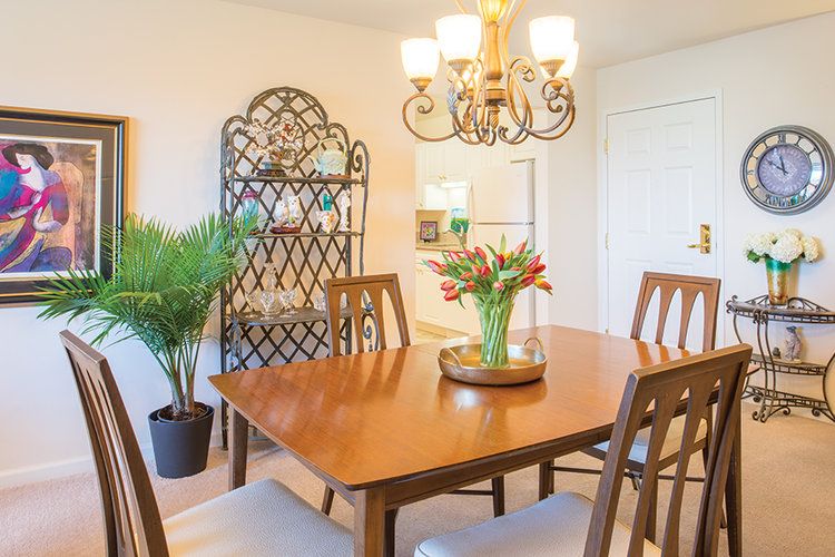 A cozy dining room with a wooden table, chairs, and a chandelier overhead.