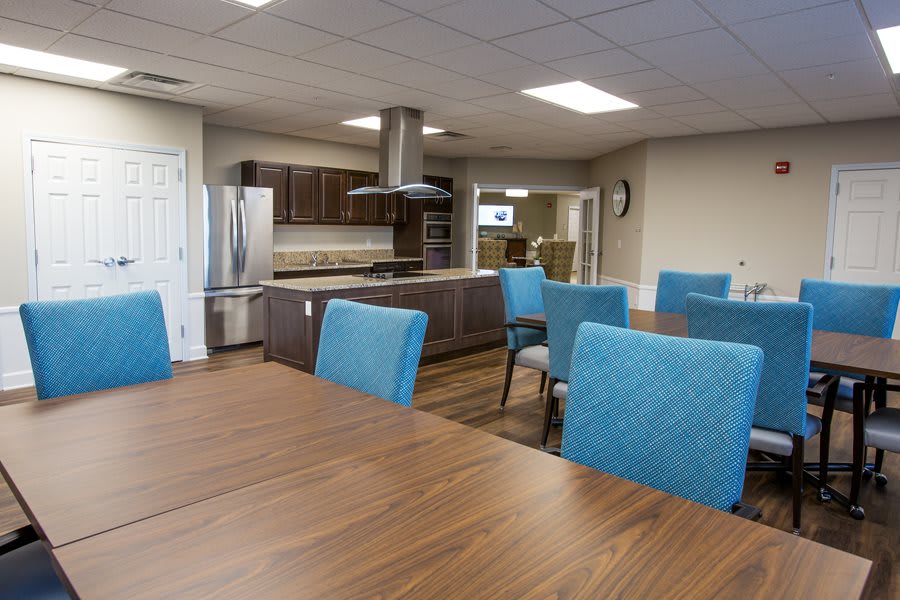 A modern kitchen and dining area with wooden tables and blue upholstered chairs.