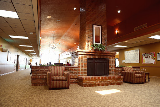 A cozy lobby area featuring comfortable chairs and a brick fireplace.