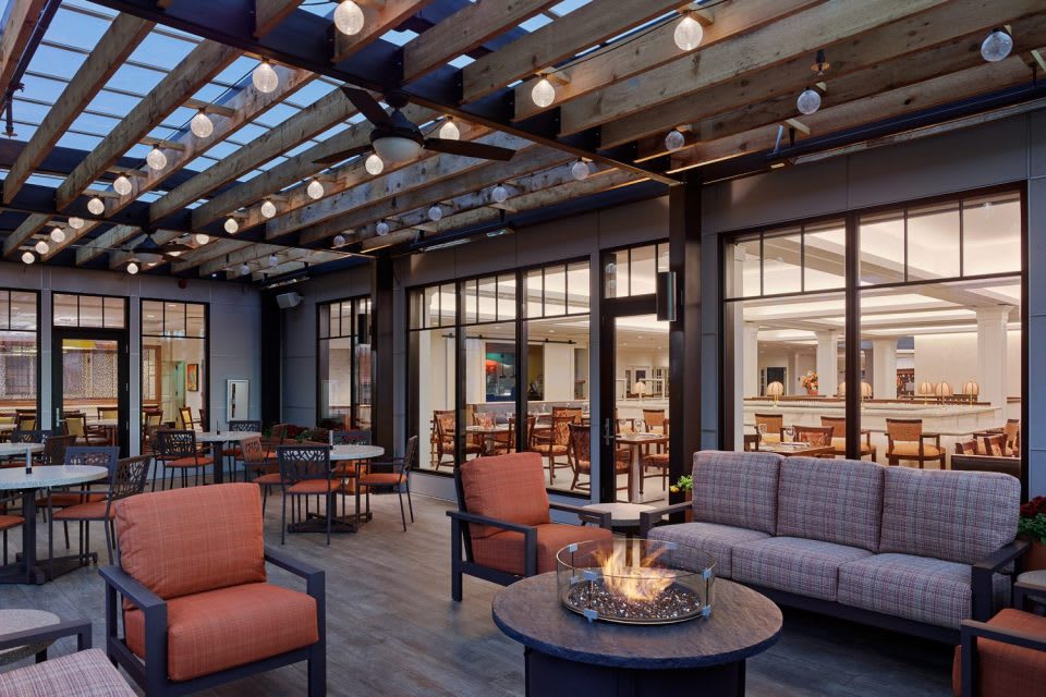 A modern patio with comfortable seating, a fire pit, and string lights creates a cozy outdoor setting.