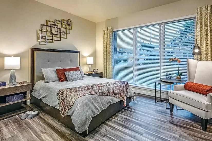 A modern bedroom with stylish decor and a large window, featuring a comfortable bed and elegant furnishings.
