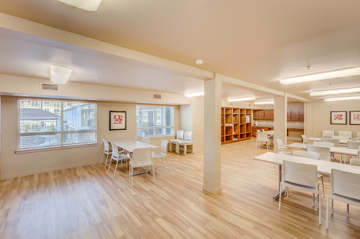 A bright and modern workspace featuring a wooden floor, tables, and ample seating.