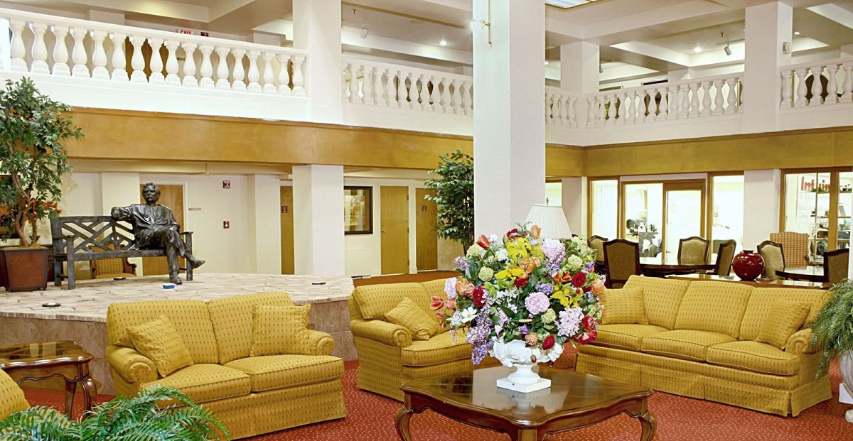 A hotel lobby with comfortable sofas, a central bouquet of flowers on a table, and elegant decor.