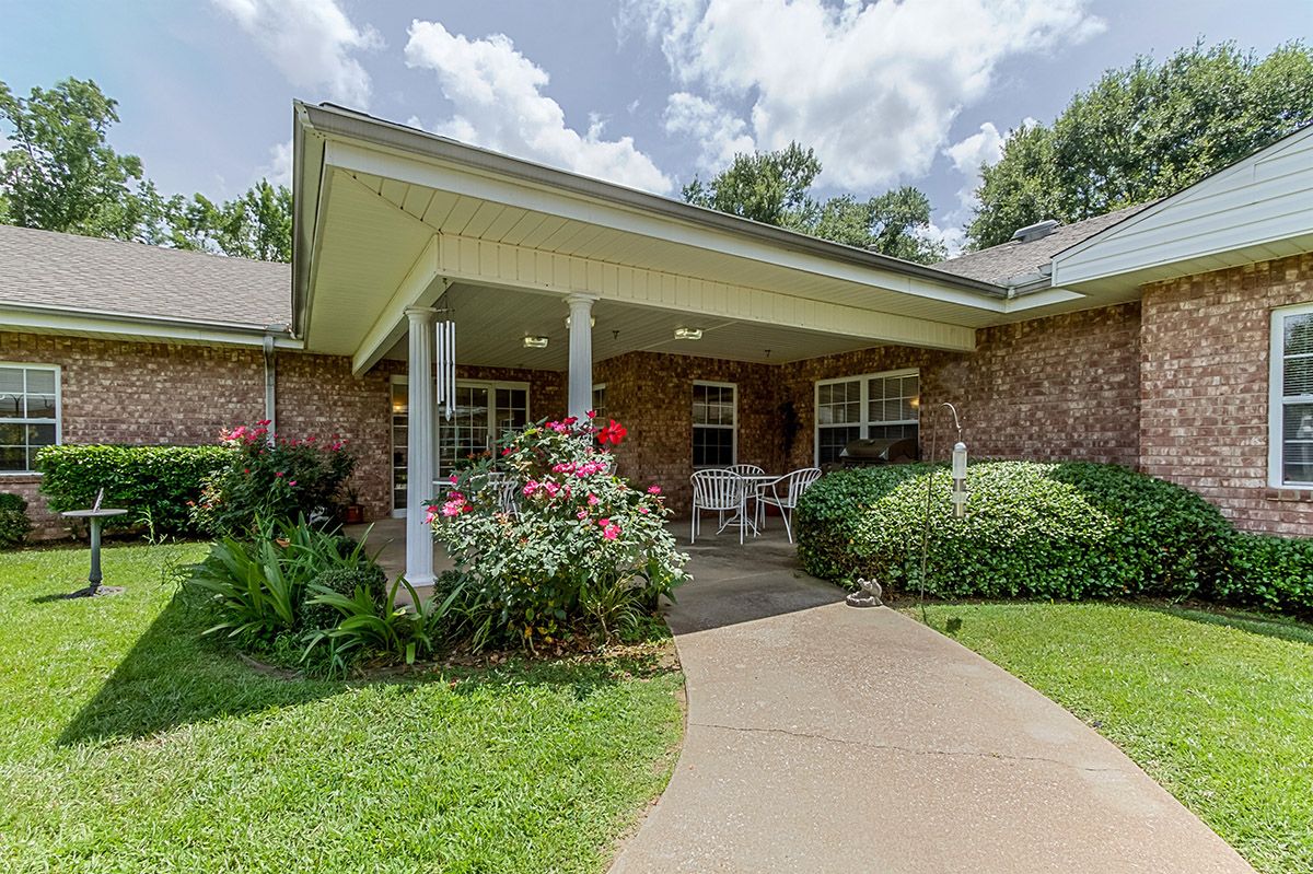 A brick house with a covered porch and well-maintained garden.