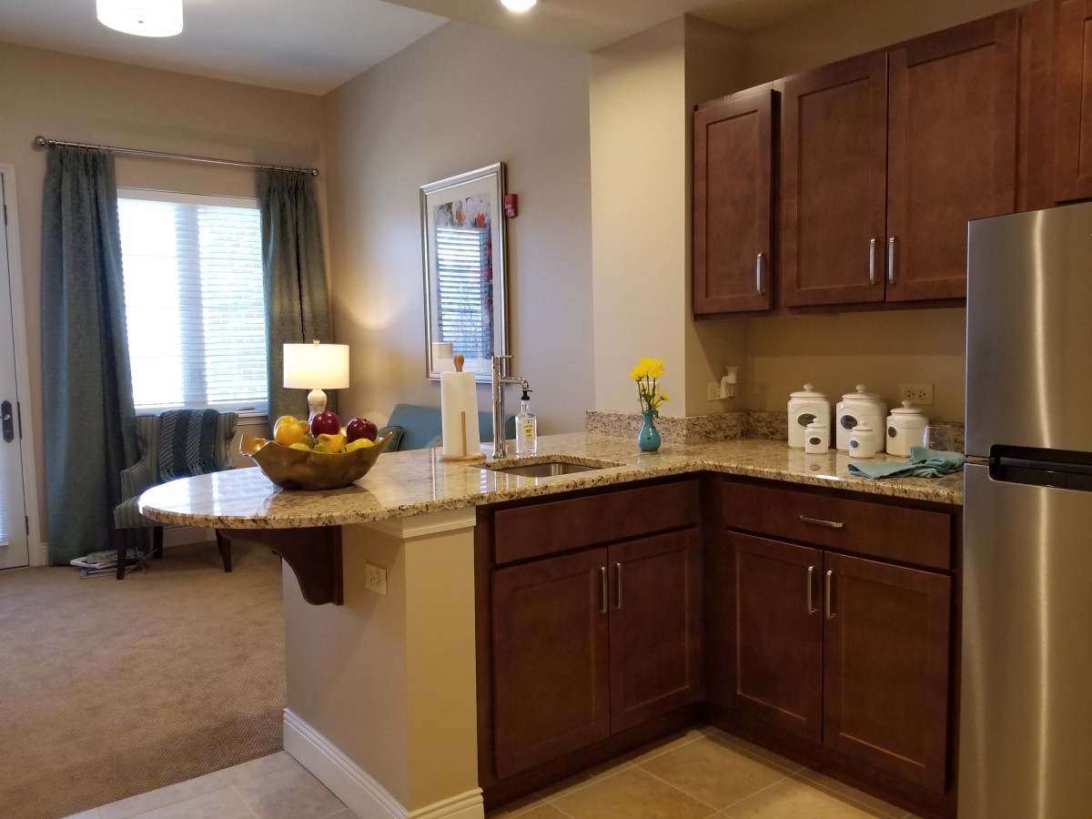 A cozy kitchen with wooden cabinets, a decorative fruit bowl, and a clean countertop.