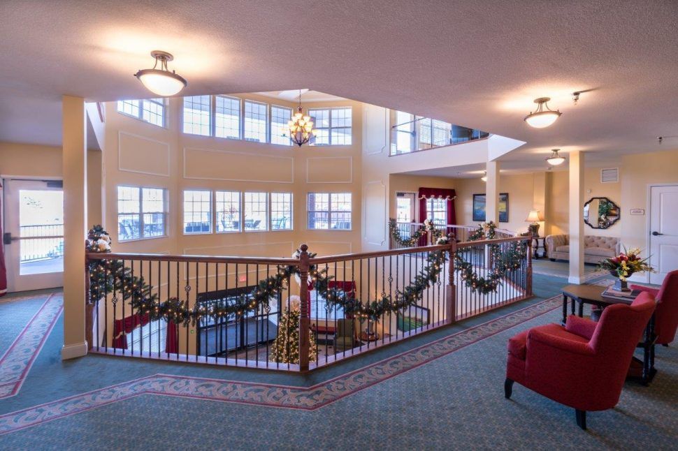 A festive lobby decorated for the holiday season, featuring garlands on the railing and ample natural light from large windows.