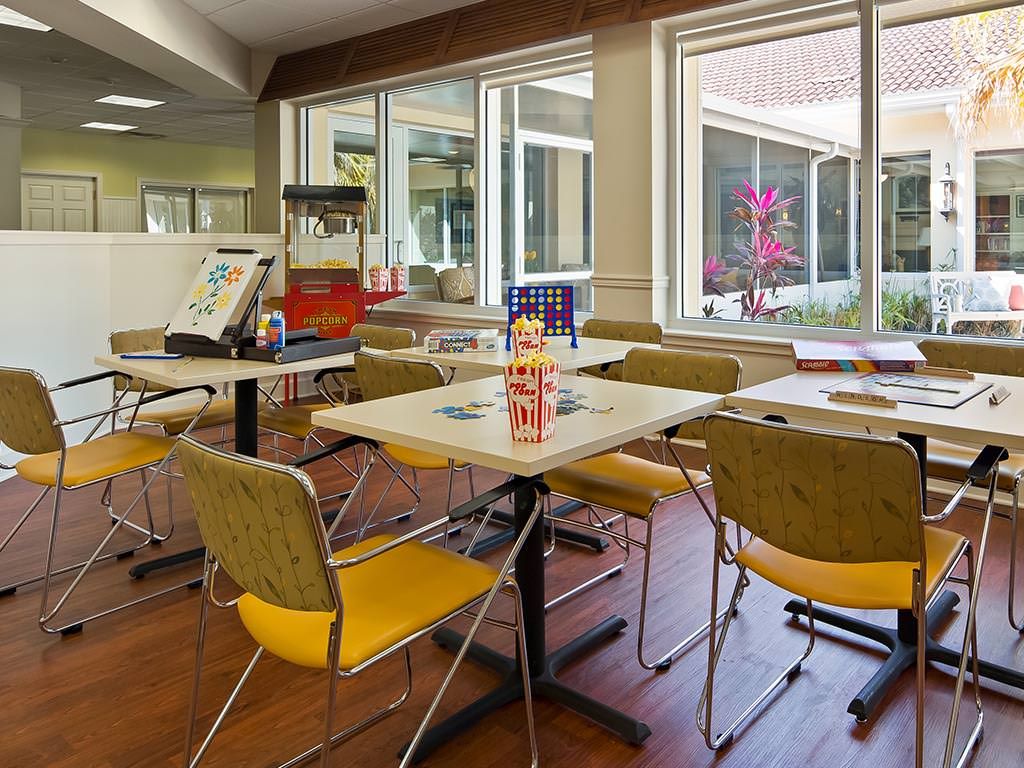 A cozy dining area with tables and chairs, featuring a popcorn machine and large windows.