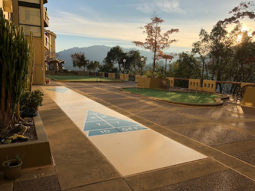 A serene view of a parking area with artistic pavement design, framed by trees and mountains under a beautiful sunset.