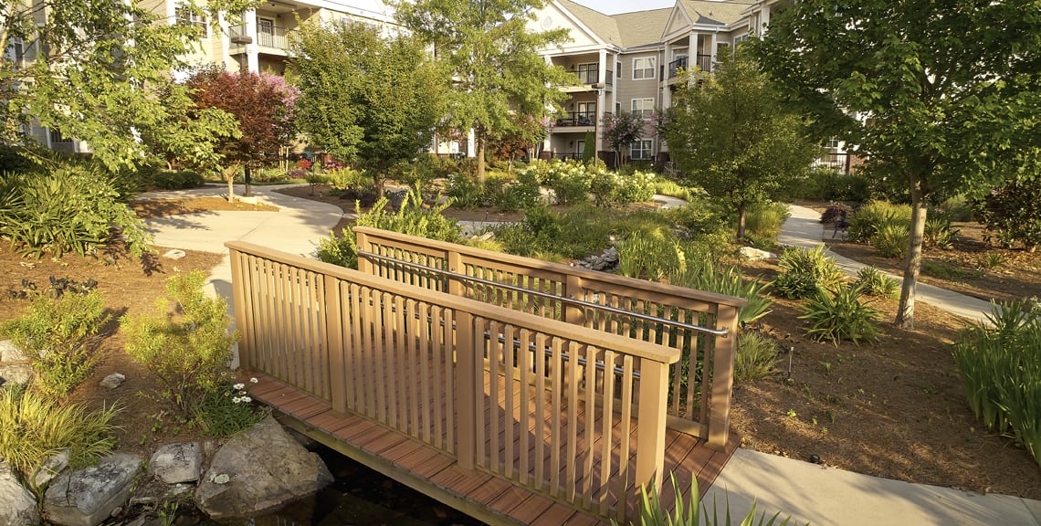 A tranquil garden scene with a wooden bridge at an apartment complex.