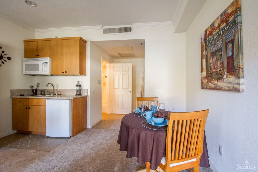 A cozy kitchen and dining area with a small table set for two in a well-lit apartment.