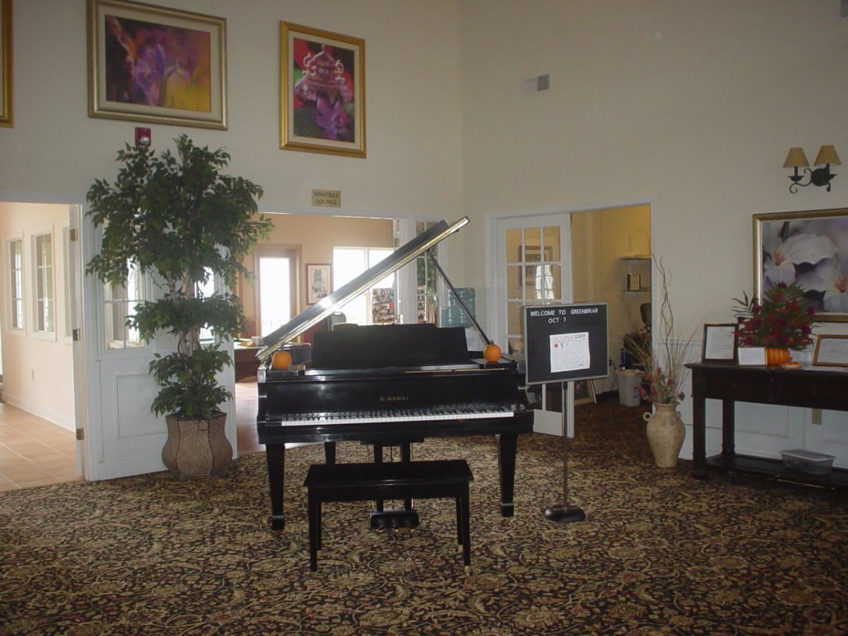 A grand piano in a well-decorated living room with artwork and plants.