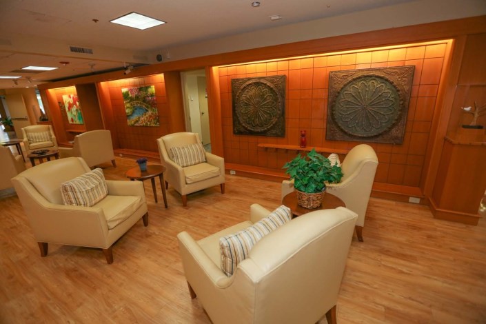 A cozy waiting room with comfortable chairs, artwork on the walls, and a small plant on a table.