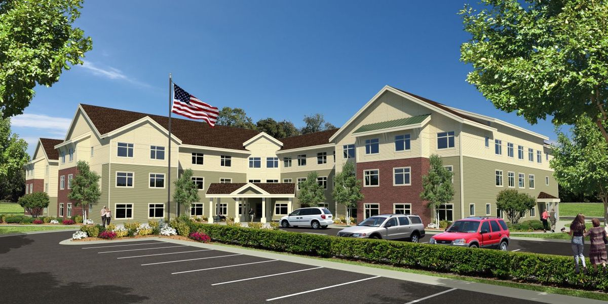 A three-story building with a parking lot and American flag in front.