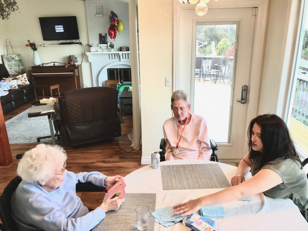 A group of people enjoying a relaxed conversation around a table in a cozy indoor setting.