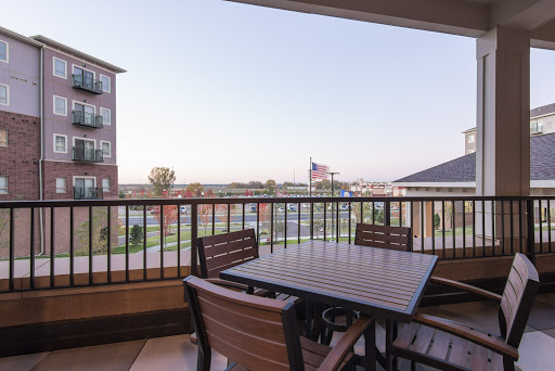 A cozy balcony with outdoor furniture offering a view of the city skyline and an American flag.