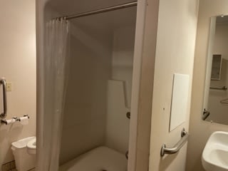 A bathroom with a shower and curtain setup.