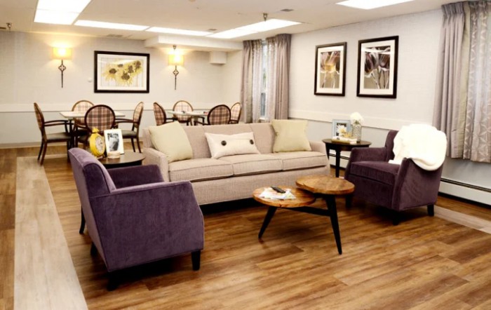 A well-decorated living room with a comfortable sofa and two chairs surrounding a wooden coffee table, featuring warm lighting and wall art.