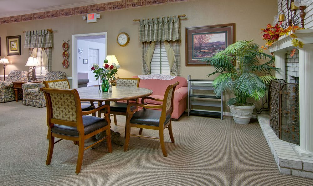 A cozy living room with a table and chairs, sofa, plants, and decorative elements.