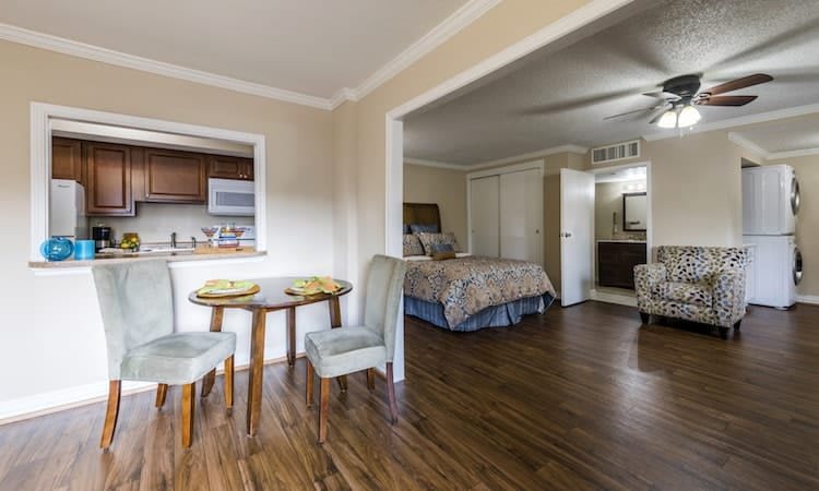Open-concept apartment with a cozy bedroom, small dining area, and view of the kitchen.