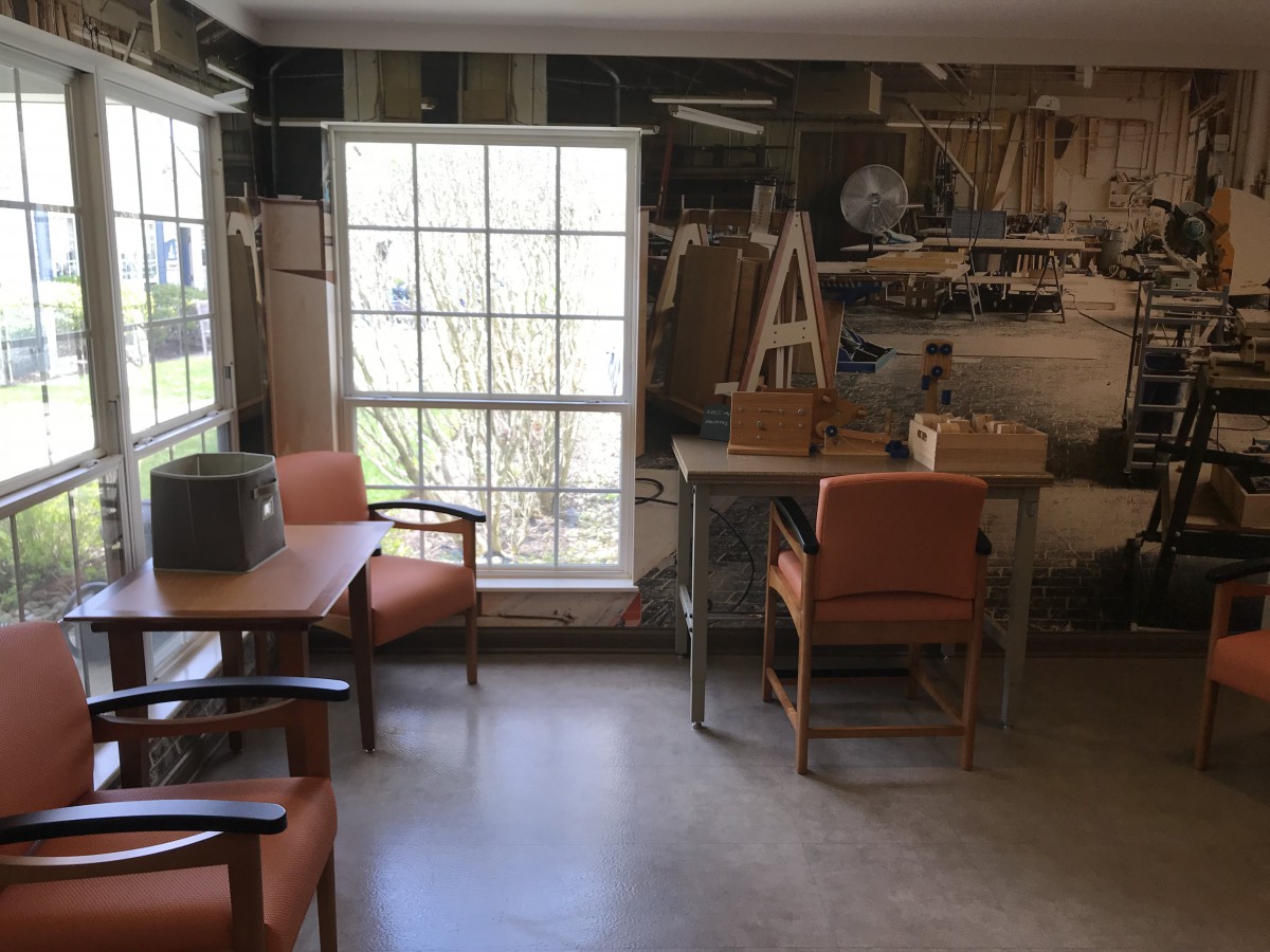 A cozy workshop room with chairs, a table, and a window allowing natural light.