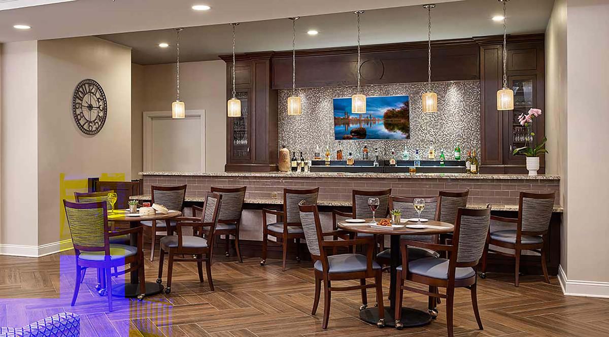 A modern restaurant interior featuring a bar and dining tables with elegant lighting and decor.