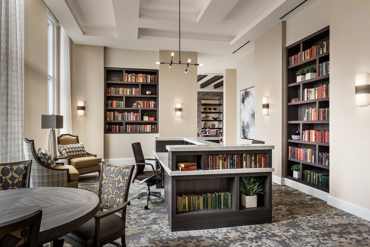 A modern library interior with bookshelves, comfortable seating, and ample lighting.