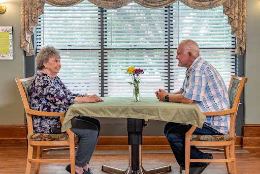 An elderly couple engaging in a heartfelt conversation over a table adorned with flowers.