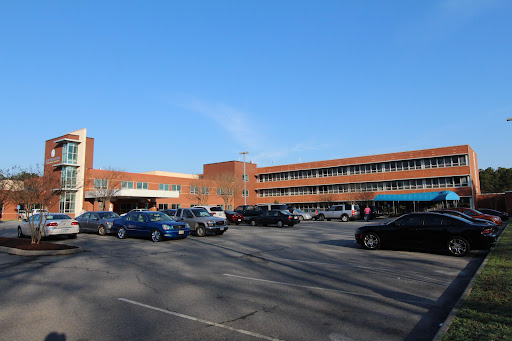 A view of a school building with a spacious parking lot under a clear blue sky.