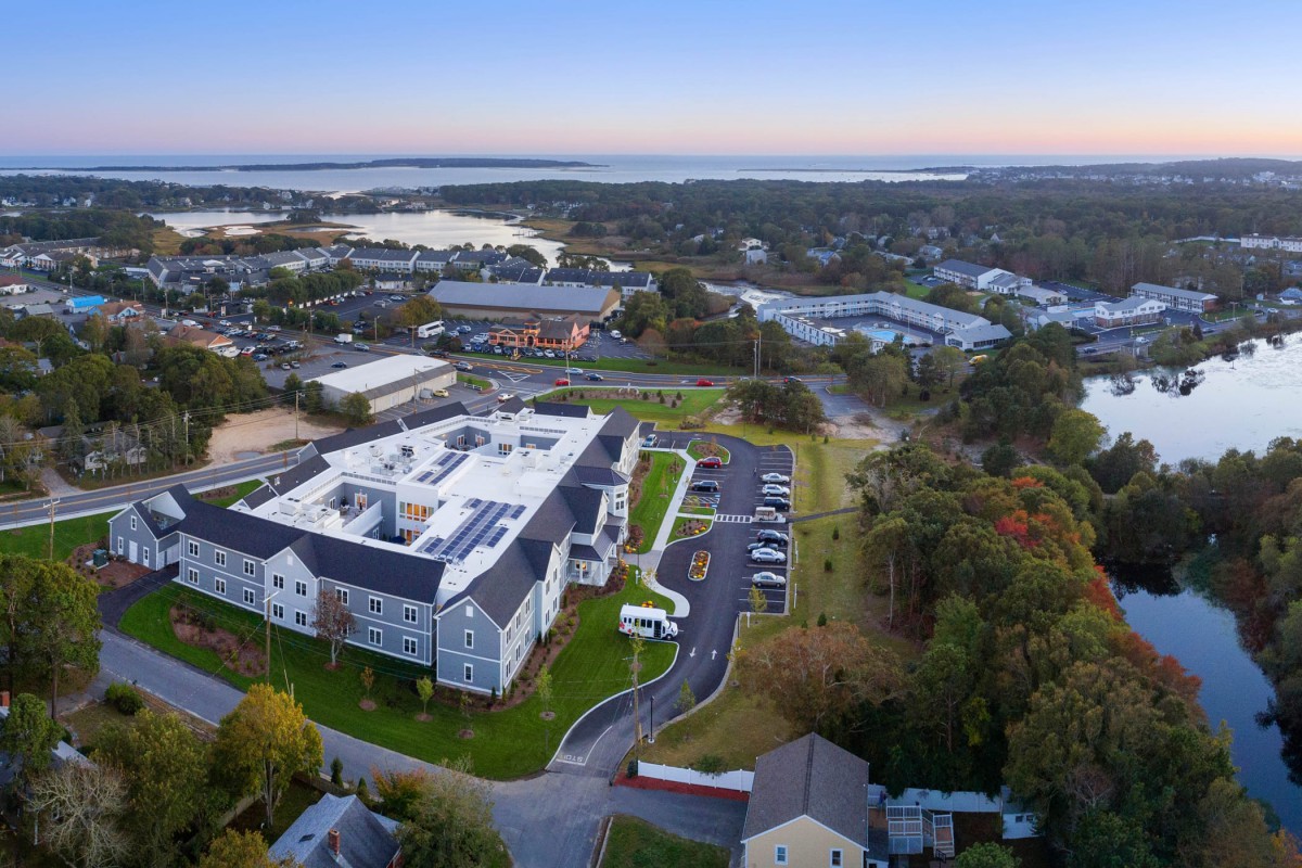 Aerial view of a coastal building surrounded by greenery at sunset.
