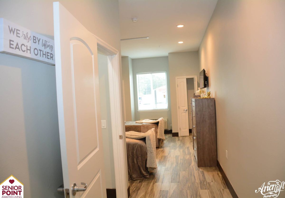 A modern, well-lit room with minimalistic furniture and a hallway leading to a window.