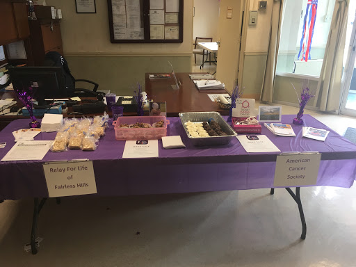 A community event display featuring various baked goods and snacks on a purple table.