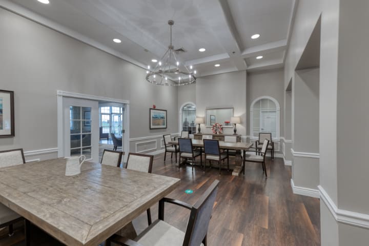 A spacious and elegantly designed dining room with a modern chandelier and hardwood flooring.