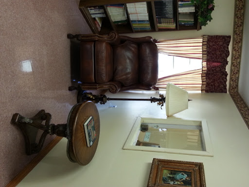A cozy living room setup featuring a leather chair, wooden table, and a bookshelf.