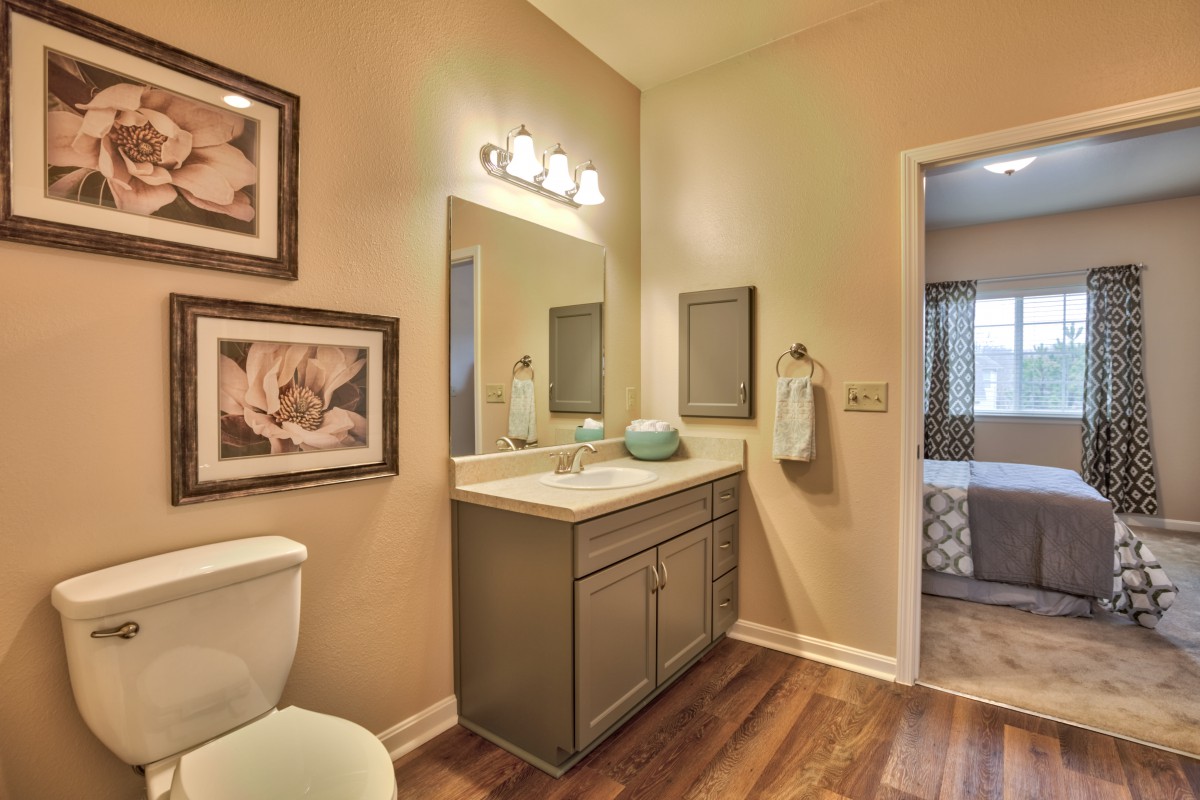 A warmly lit bathroom featuring a sink, mirror, and wall decor.
