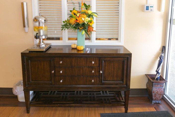 A dark wooden console table adorned with a vibrant floral arrangement in a light blue vase.