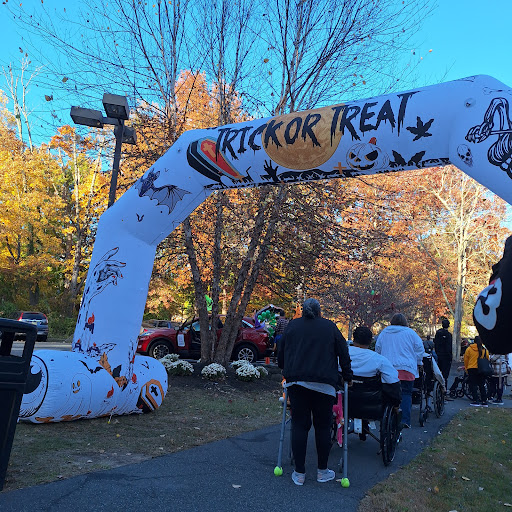Families gather under a festive 'Trick or Treat' arch during a Halloween event.