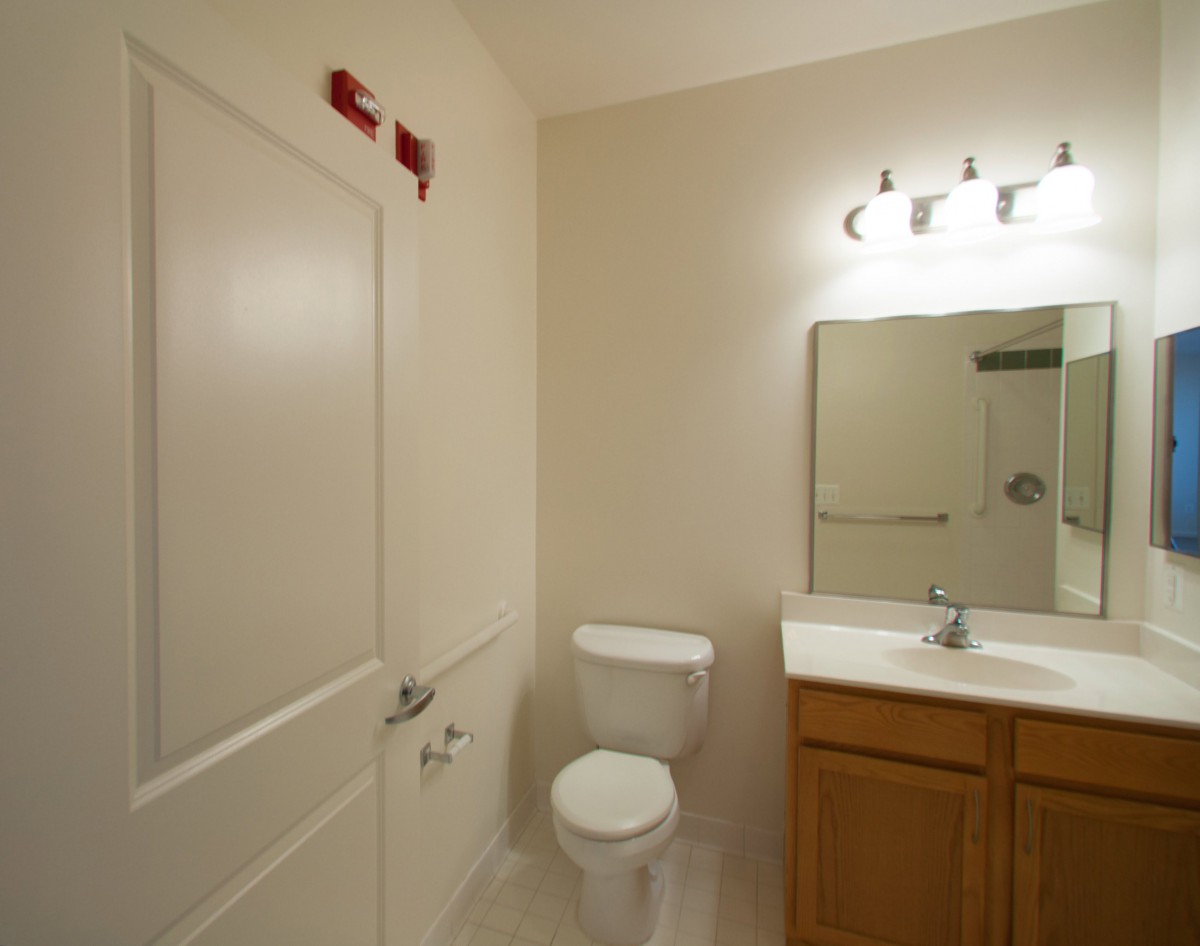 A simple bathroom with a toilet, sink, and mirror.