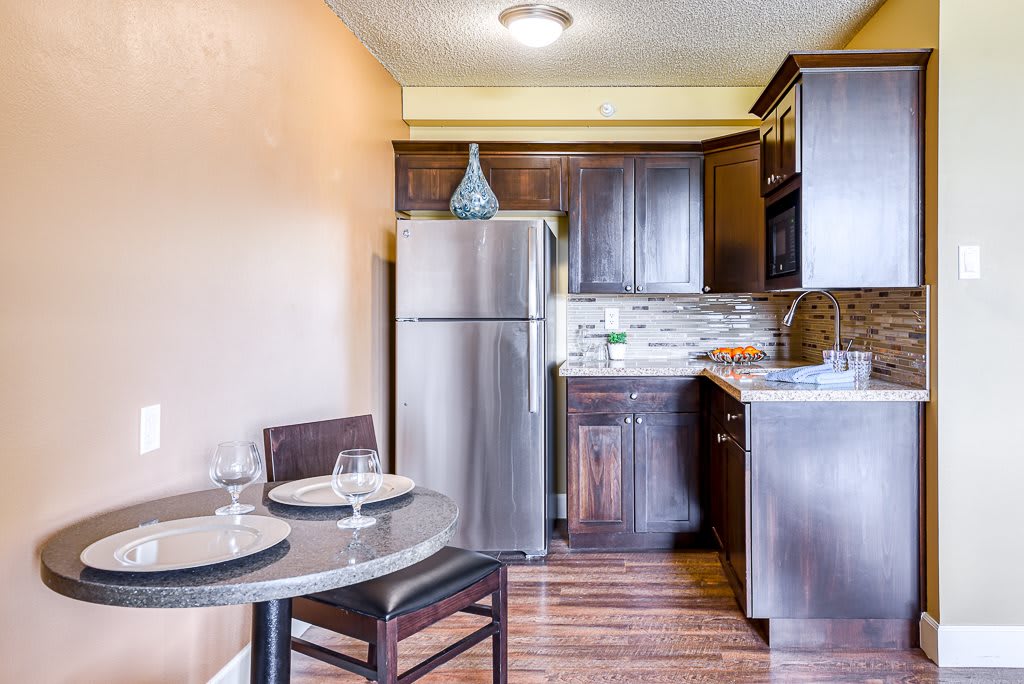 A modern kitchen with wooden cabinets and a small dining area.