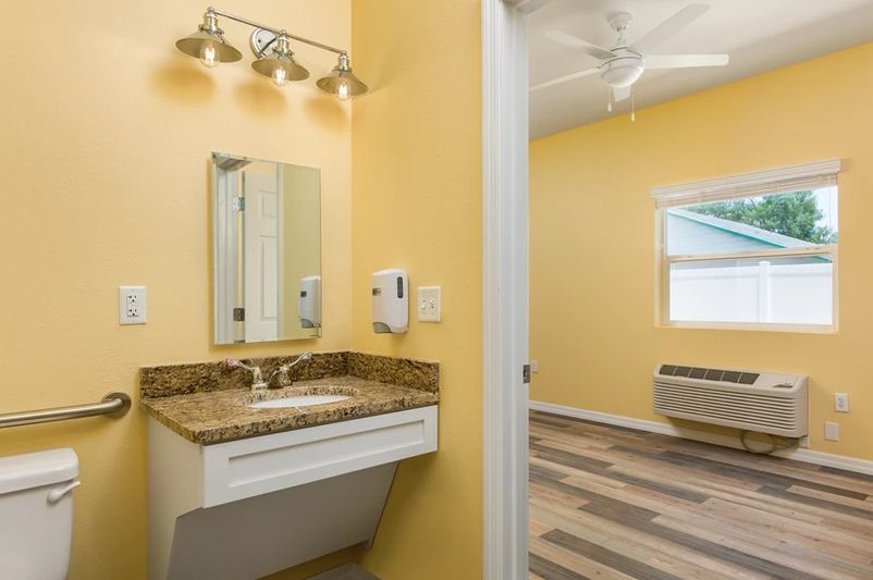 A bathroom with yellow walls features a sink, mirror, and modern lighting fixture.