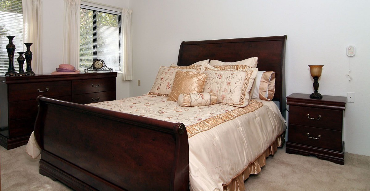 A cozy bedroom with a neatly made bed and elegant bedding.
