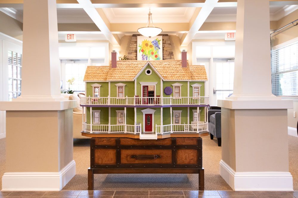 A detailed dollhouse model displayed on a wooden table in an interior setting.
