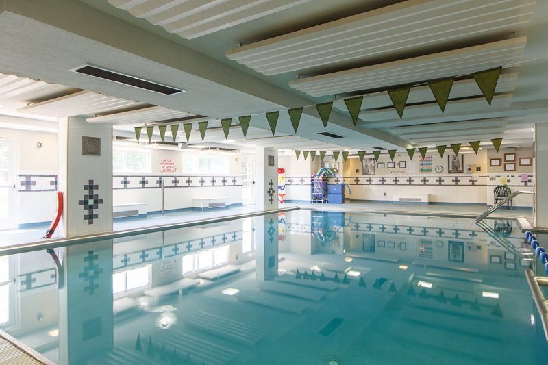 An indoor swimming pool with marked lanes and a high ceiling.
