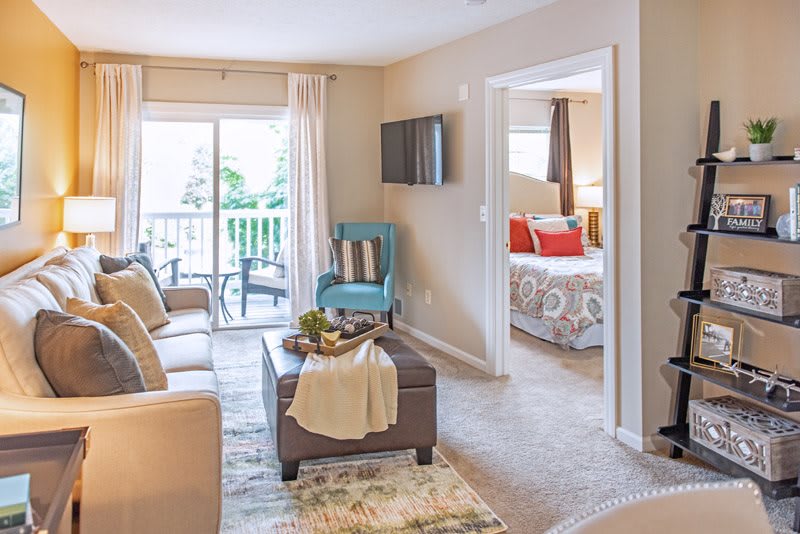 A cozy living room in an apartment featuring a couch, TV, and access to a balcony.