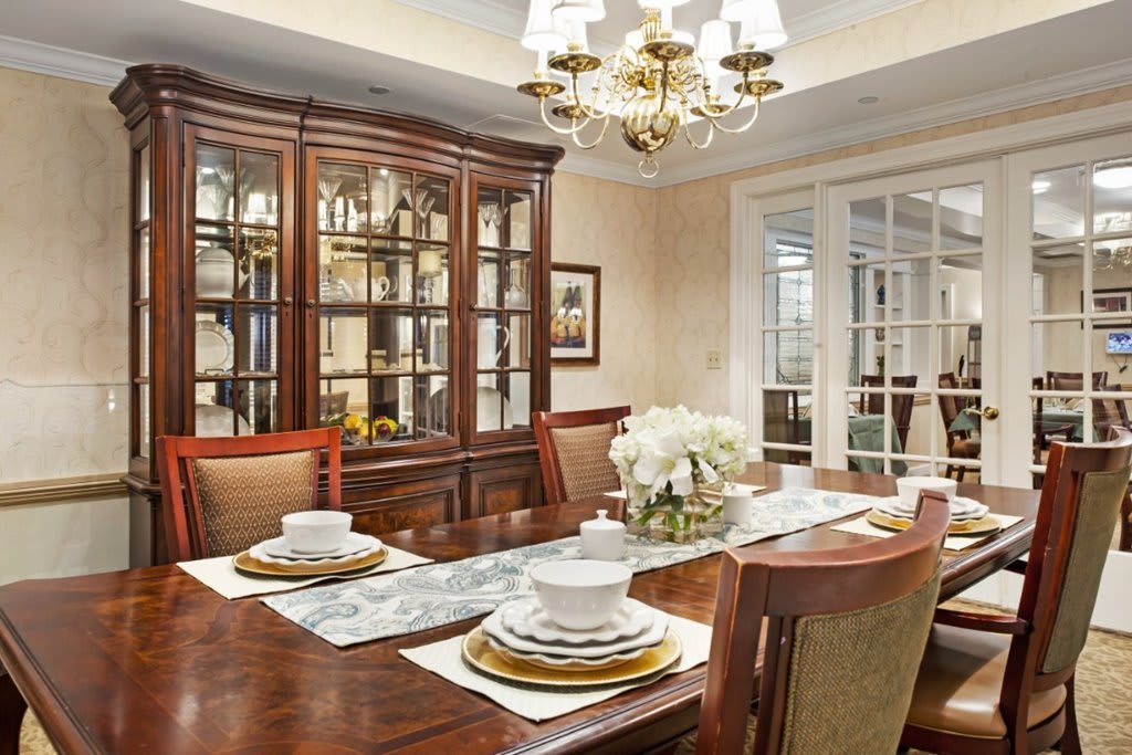 Elegant dining room with a set table, a chandelier, and a china cabinet.