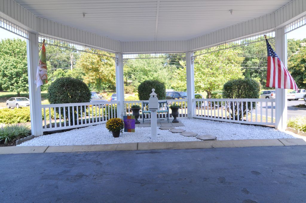 A serene outdoor gazebo with decorative flowers and a garden backdrop.